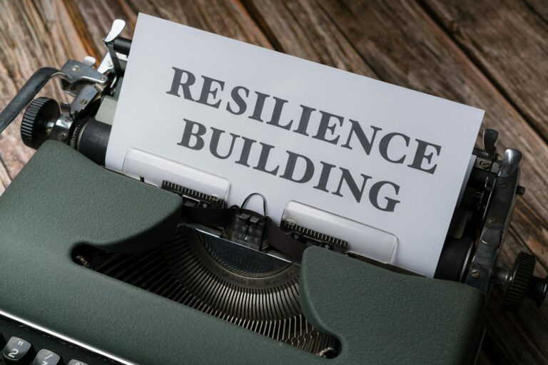 A vintage typewriter with the words 'RESILIENCE BUILDING' on a paper sheet.